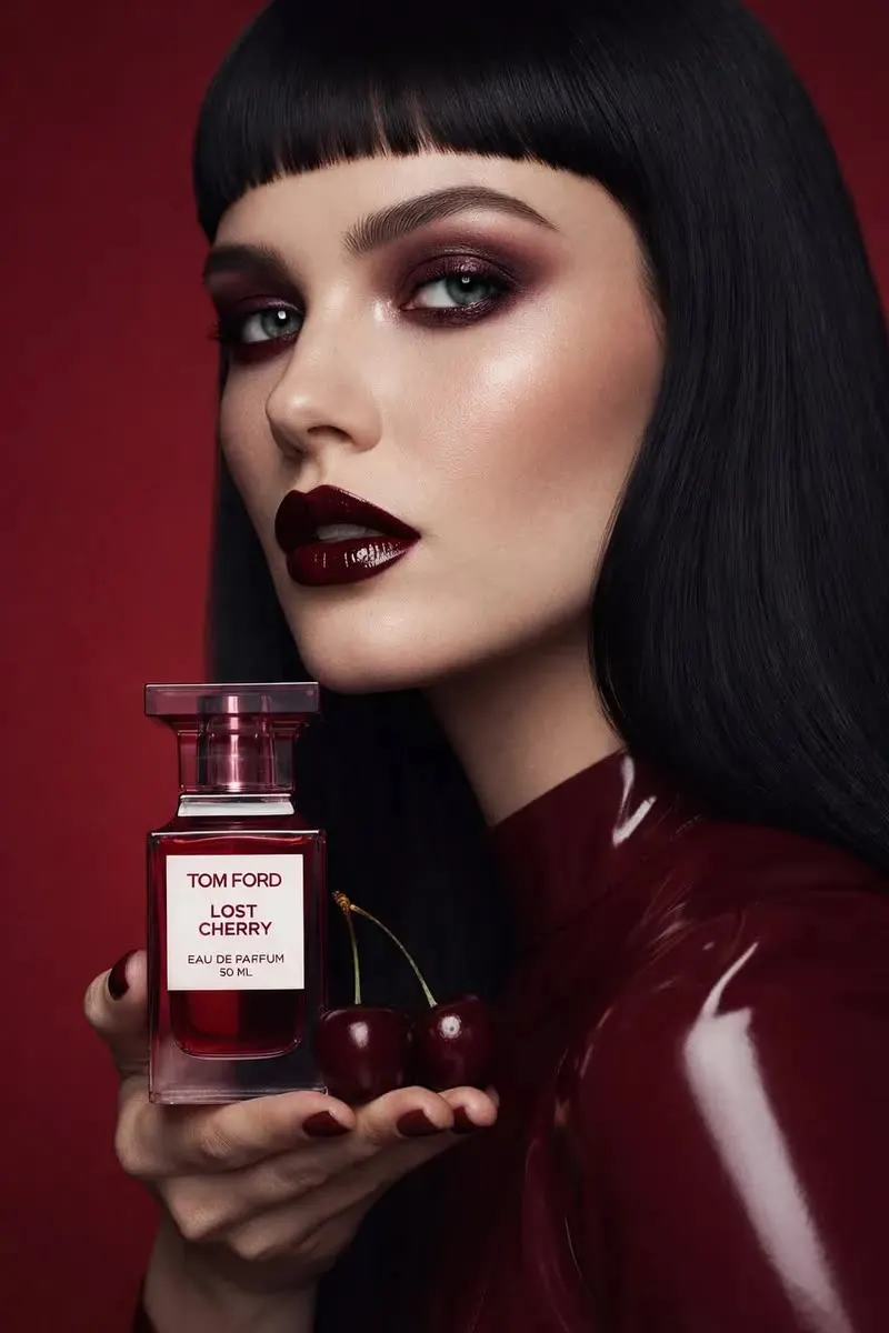 In hand template: model holding a red perfume bottle beside cherries